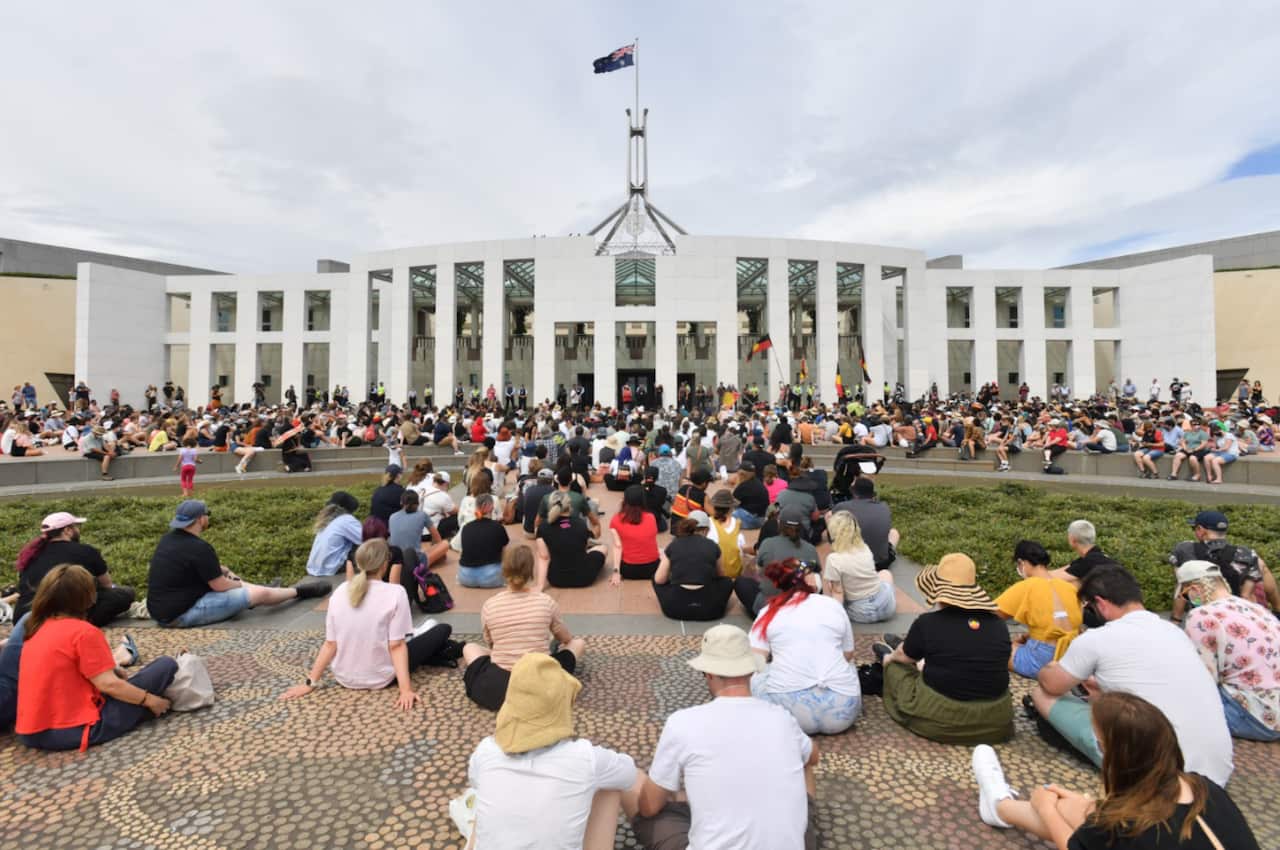 Protesters sit outside the front of Parliament House in Canberra.