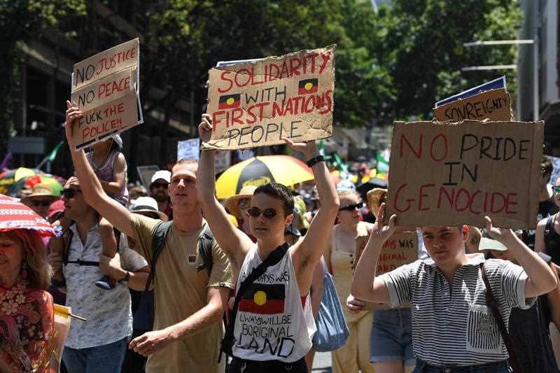 Sydney protesters hold signs aloft as they march. Thousands have rallied across Australia, demanding a change to the date of Australia Day.