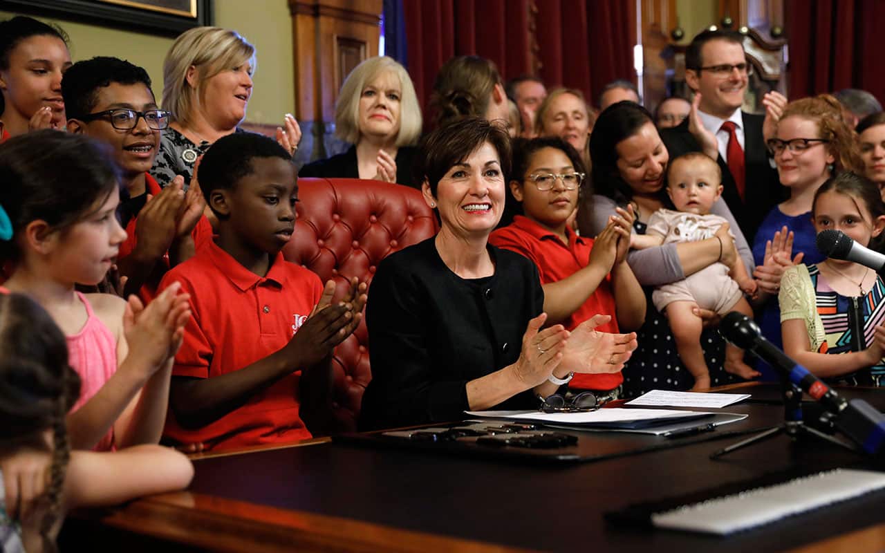 Iowa Gov. Kim Reynolds, center, reacts after signing a six-week abortion ban bill into law during a ceremony in her formal office, Friday, May 4, 2018