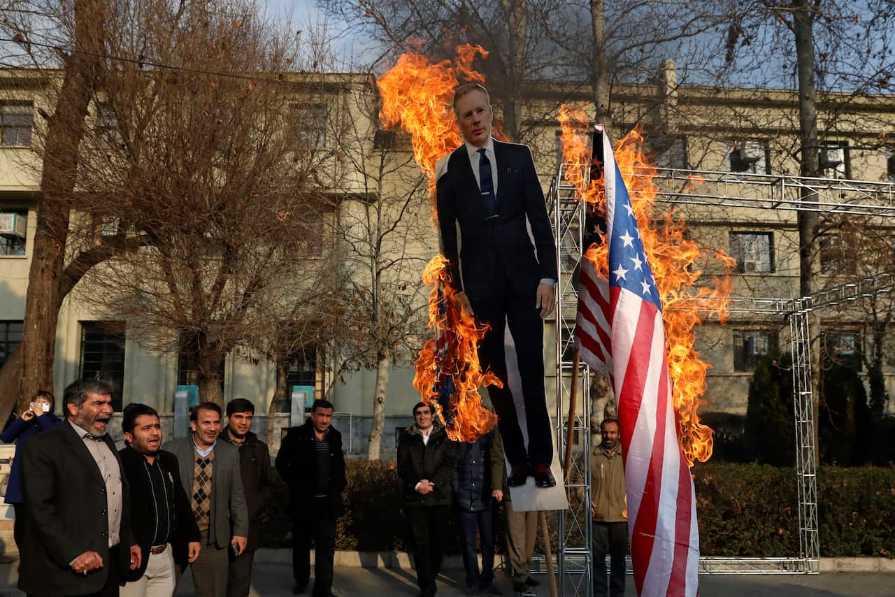 Pro-Iranian government protesters set fire to the US and British flags and a life size cut out of British ambassador to Tehran, Rob Macaire.