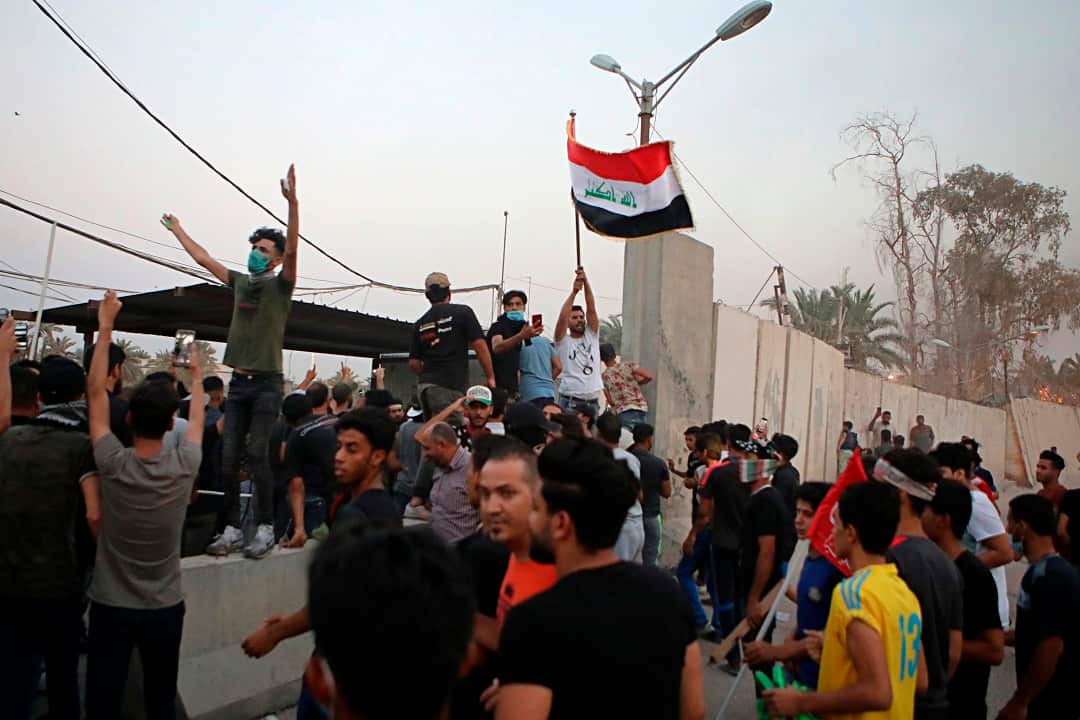 Protesters raise the Iraqi flag at the gate of the Iranian consulate building before storming and burning it in Basra.