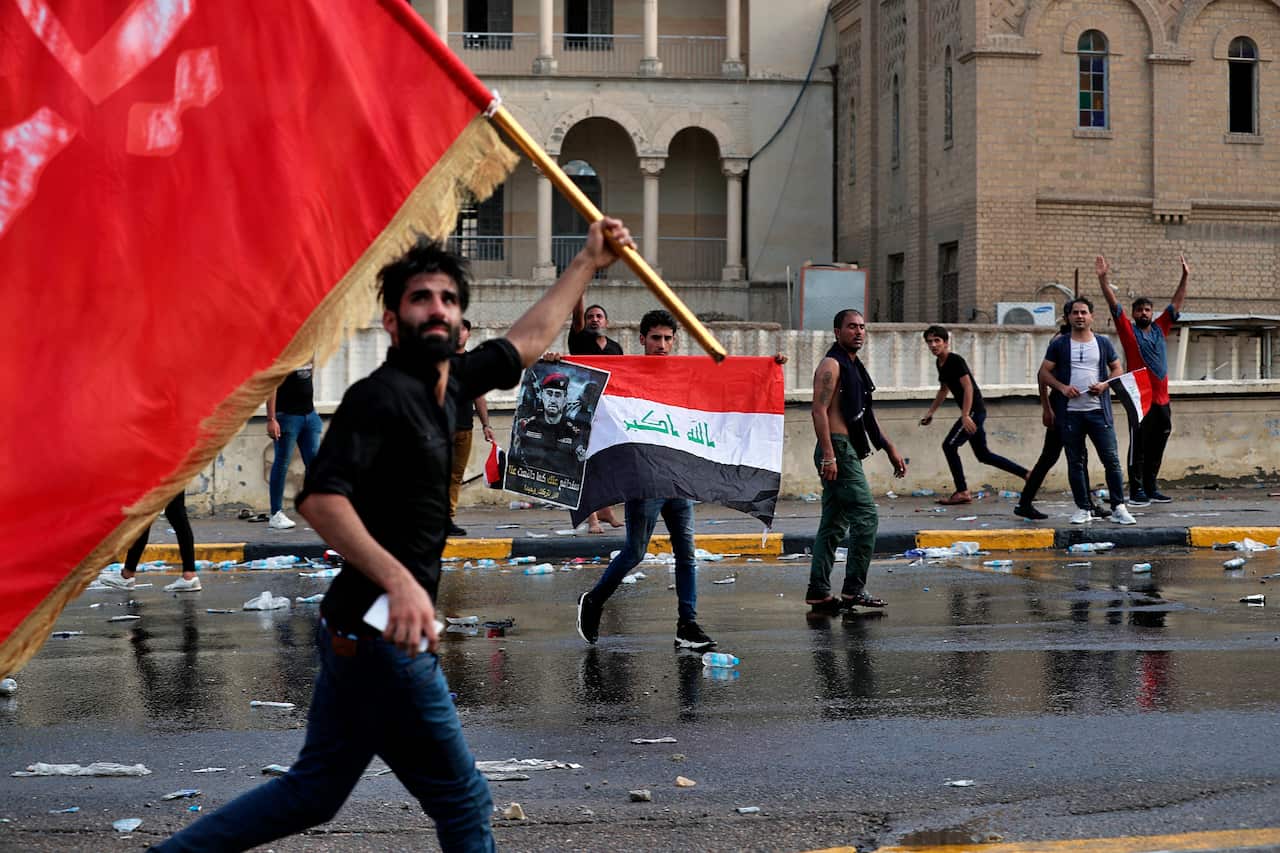Protesters wave flags and hold a poster of Lt. Gen. Abdul-Wahab al-Saadi during a protest in Tahrir Square, in central Baghdad, Iraq.