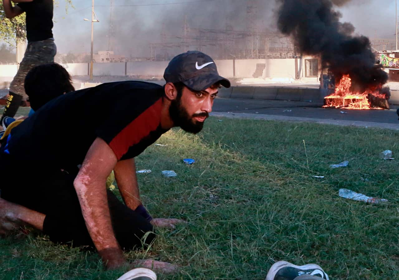 A protestor takes cover while Iraq security forces fire during a demonstration in Baghdad.