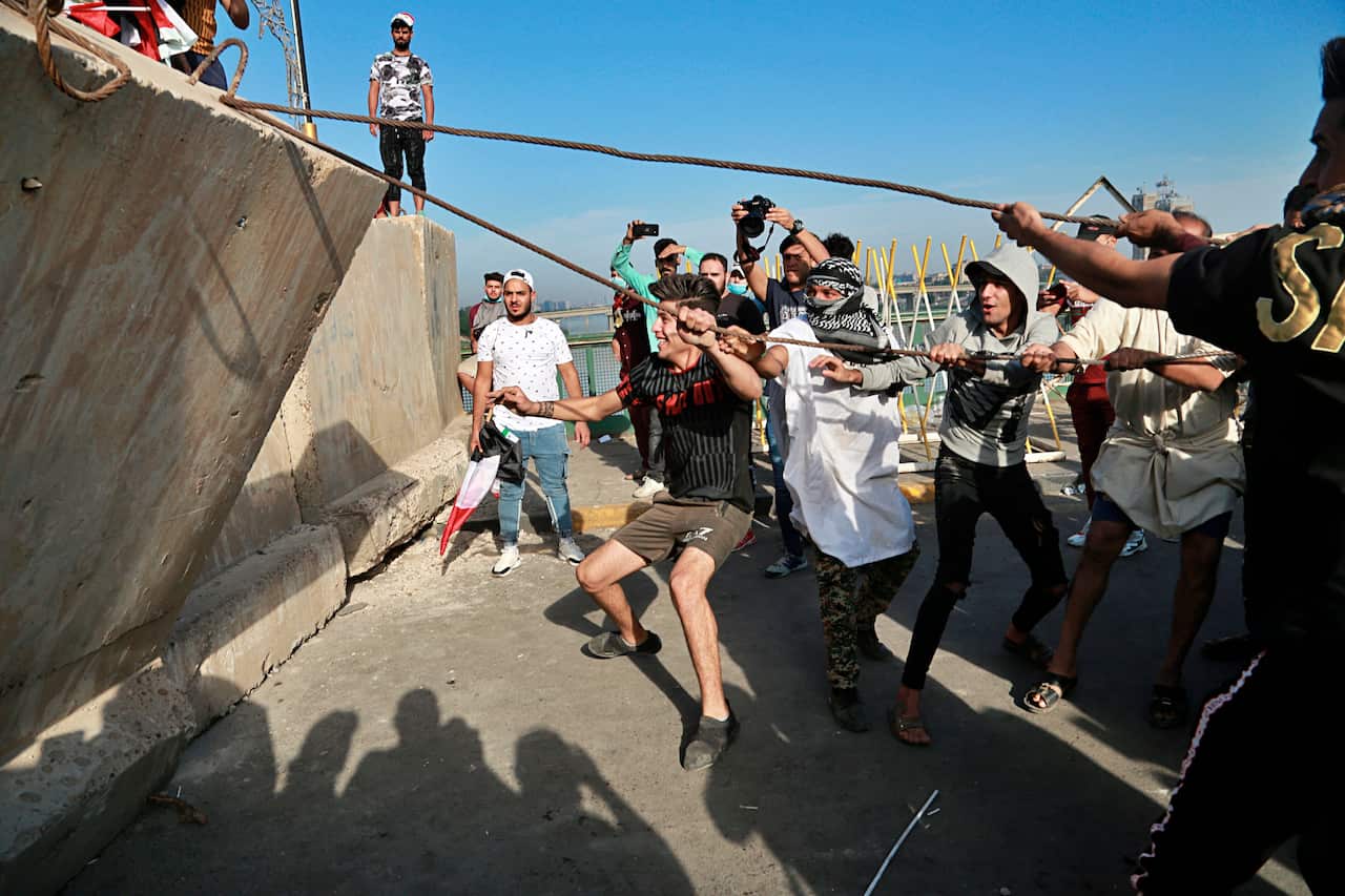 Anti-government protesters pull down concrete walls leading to the heavily guarded Green Zone during a demonstration in central Baghdad.