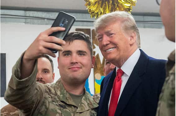 US President Donald Trump takes a photo as he greets members of the US military.