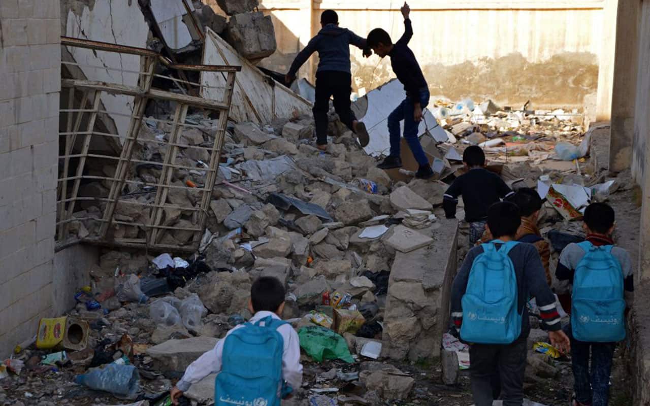 Iraqi children walk in the rubble as they head to school in the battered city of Mosul on December 27, 2017. 