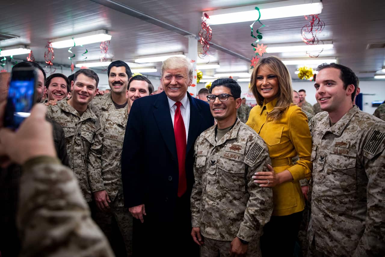 President Trump and Melania Trump pose for photos as they greet members of the United States military in a dining hall at al-Asad air base, Iraq.