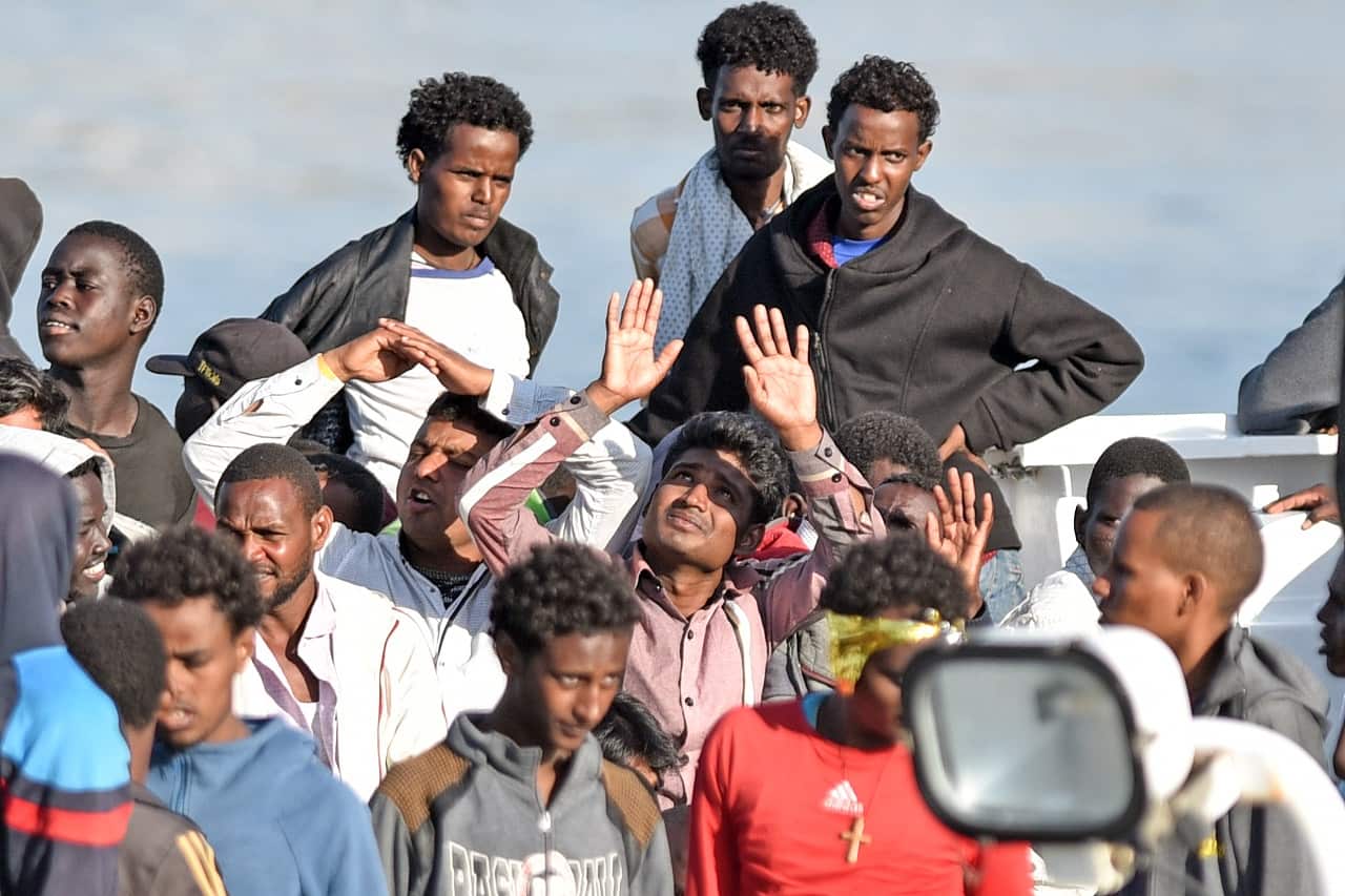 Men wait to disembark from the Italian Coast Guard vessel "Diciotti" following a rescue operation.
