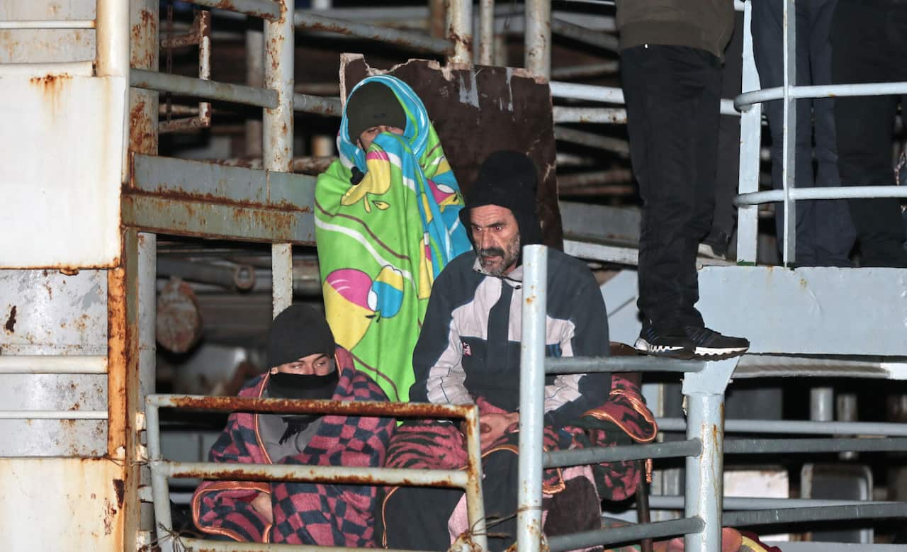 Two men wait as the cargo ship Ezadeen, carrying hundreds of migrants, arrives at the southern Italian port of Corigliano, Italy, on January. 2, 2015. (AAP)