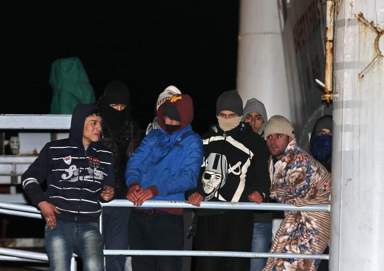 Young men wait to disembark the cargo ship Ezadeen, which smugglers sent speeding toward the coast in rough seas with no one in command. (AAP)