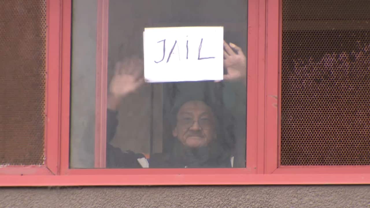 A resident of one of the towers holds a sign with the word 'jail' on it.