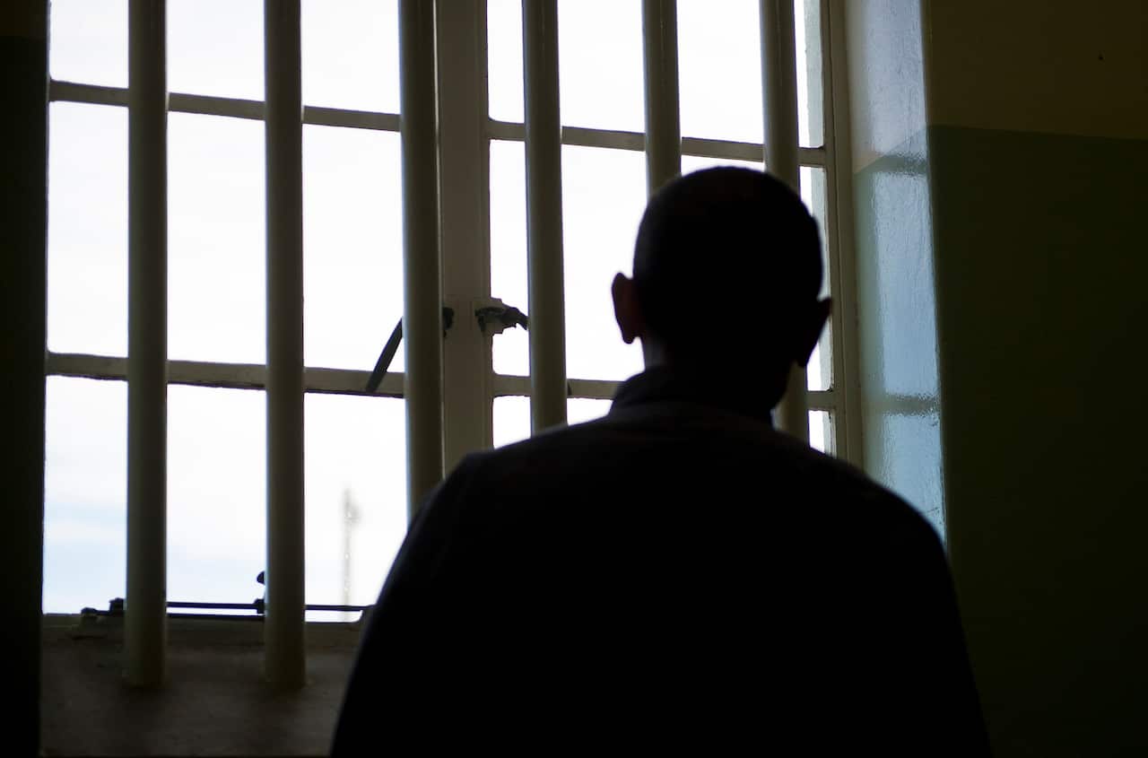 A silhouette of a man behind bars.