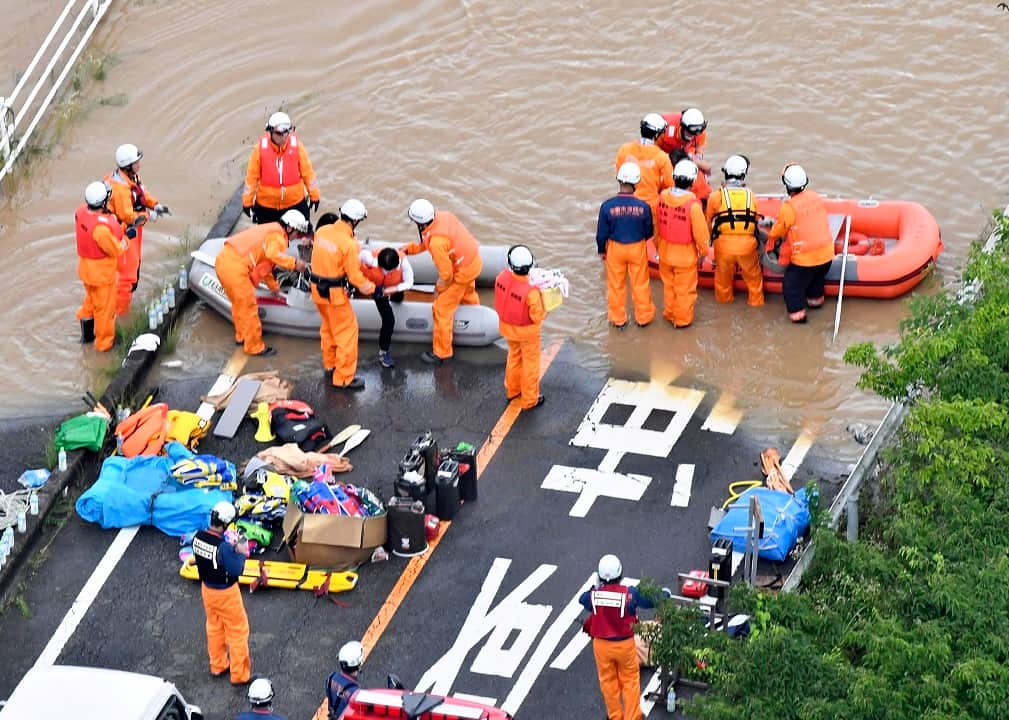 An aerial photo shows fire fighters helping residents to get off boats in Kurashiki.