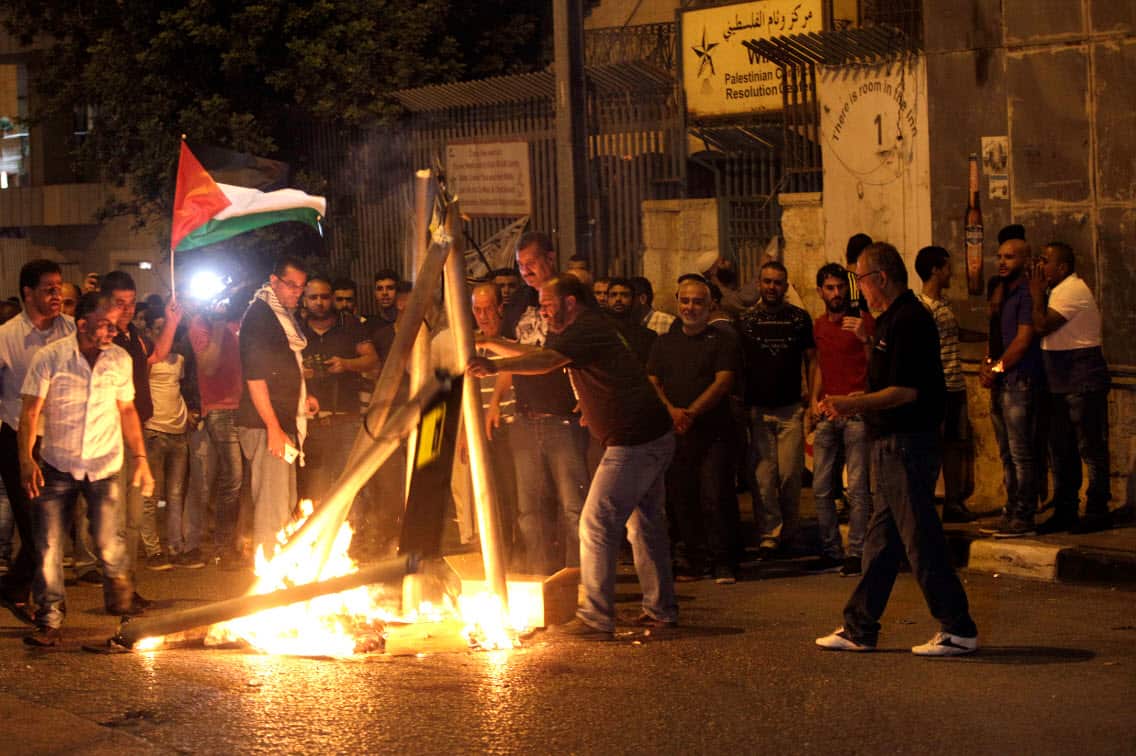 Palestinians burn mock metal detectors during a demonstration in Bethlehem, Sunday, July 23, 2017.