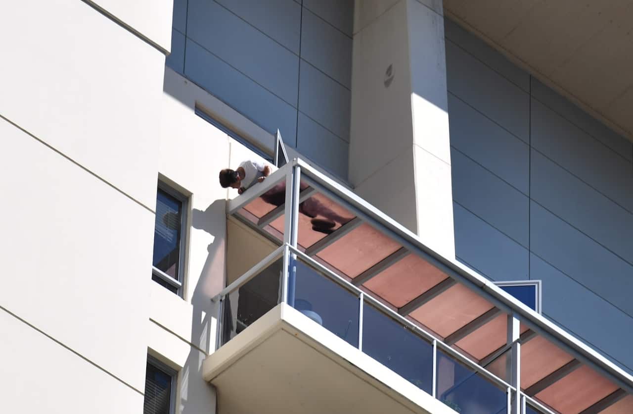 A man is seen on a ledge on an apartment building in Chatswood, Sydney, Monday, October 9, 2017. 