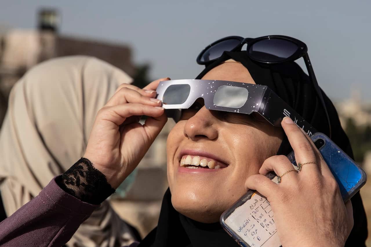 People view the partial solar eclipse at the Citadel in downtown Amman, Jordan.