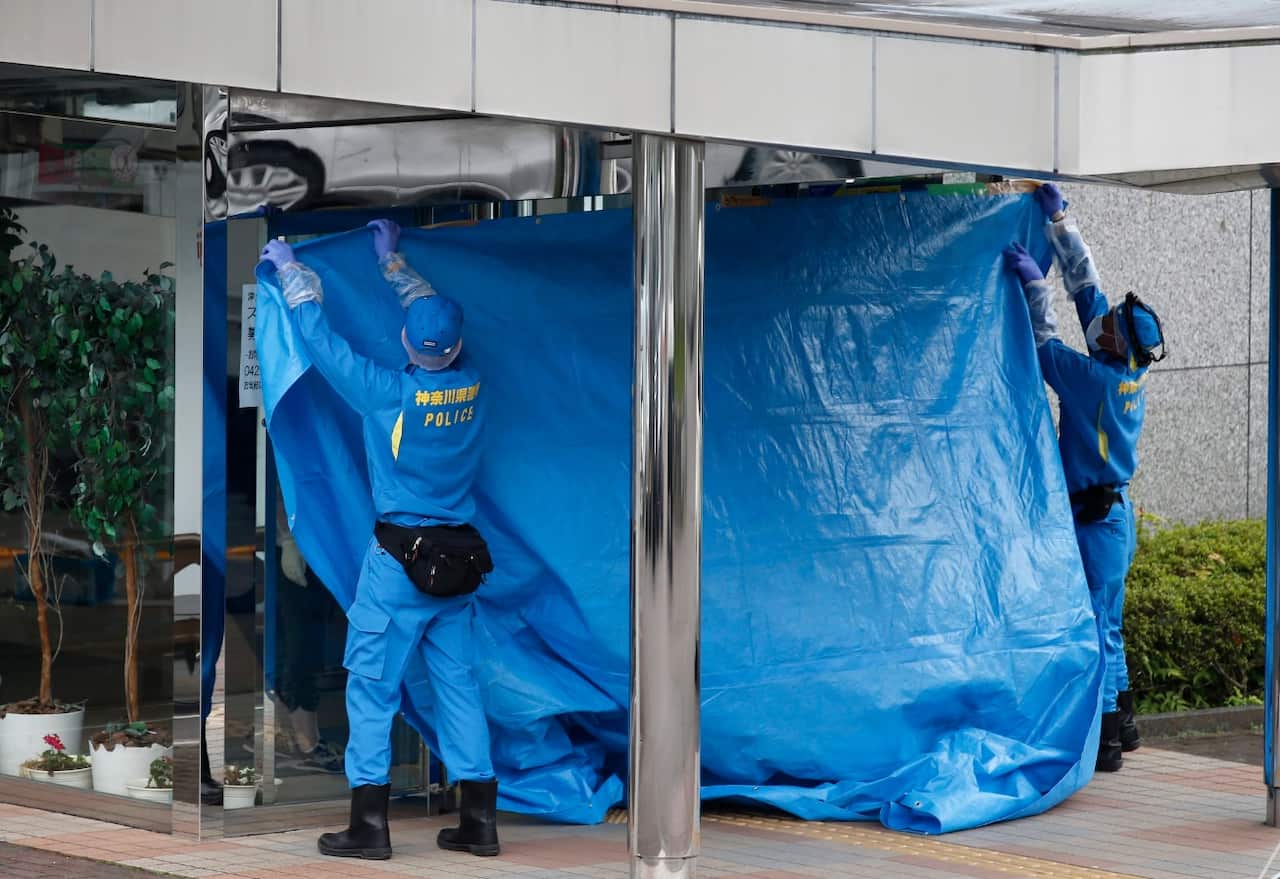 Police identification unit officers cover the front entrance with a blue plastic sheet to investigate inside (AAP)