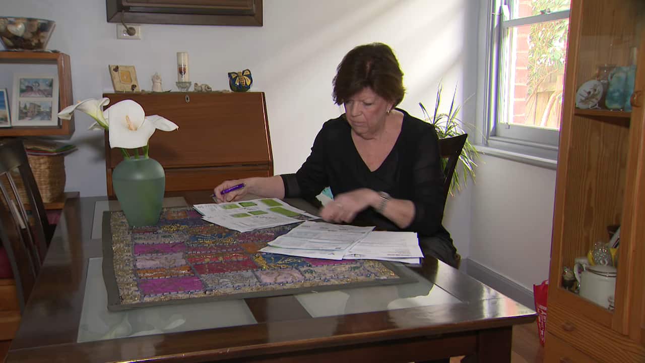 Judy Little looks at her bills in her Melbourne home