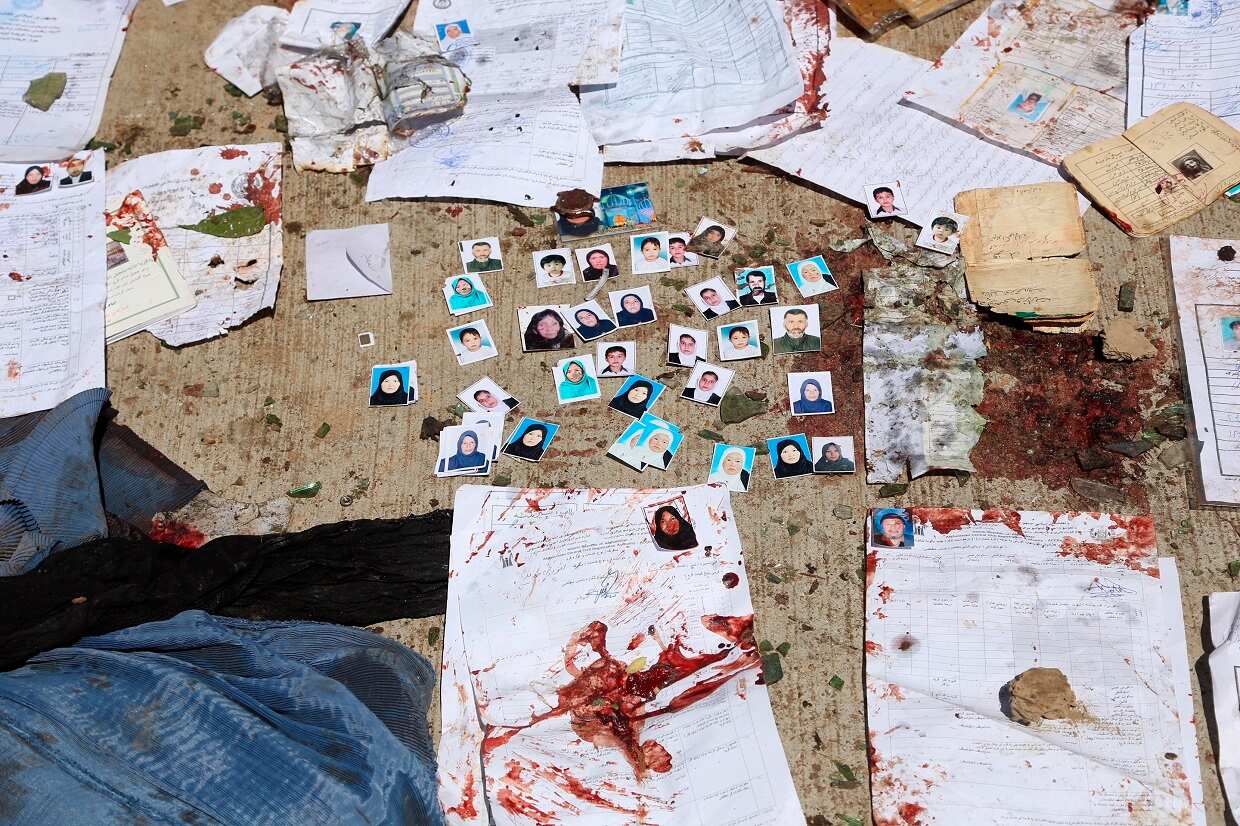 Blood-stained National ID papers and voters' photos are seen on the ground outside a voter registration center, after a suicide attack in Kabul, Sunday, April 22, 2018. (AP Photo/ Rahmat Gul)