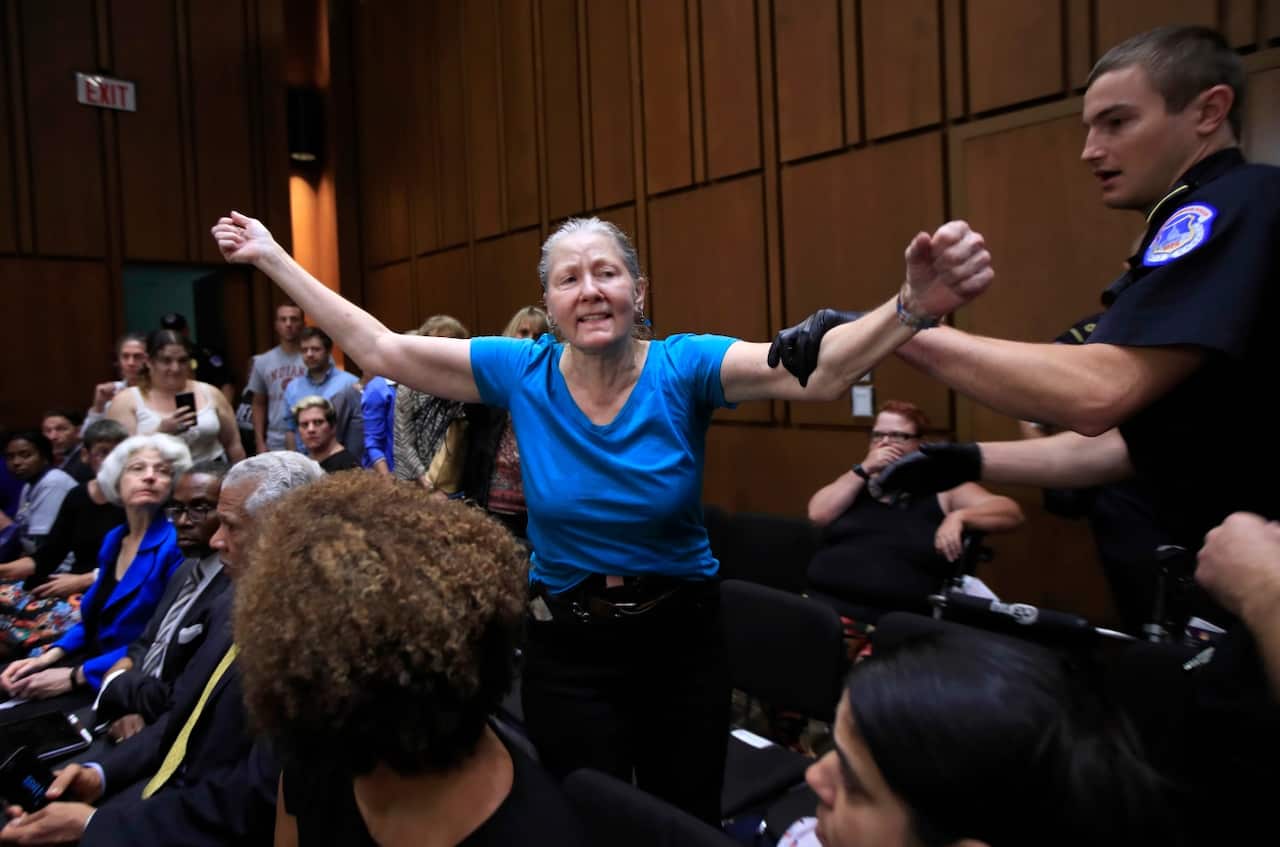 A protester is restrained by a U.S. Capitol Police officer during a Senate Judiciary Committee nominations hearing on Supreme Court nominee Brett Kavanaugh