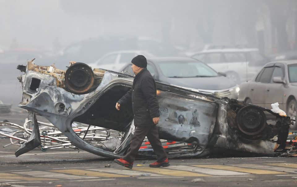A man walks past a car that was burned during the protests triggered by fuel price increases in Almaty, Kazakhstan, 6 Janury, 2021.