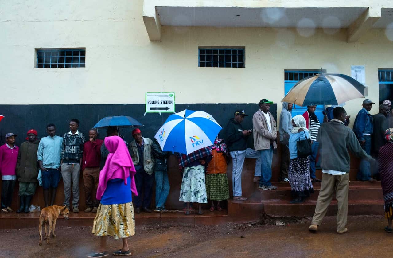 Kenyans brave the rain to cast their votes at Mutomo Primary School polling station in Gatundu, Kenya, 26 October 2017 (AAP)