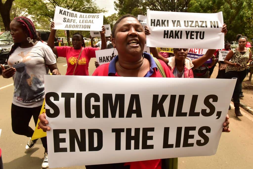 An activist holds up a placard reading 'Stigma kills, end the lies' during a demonstration in Nairobi