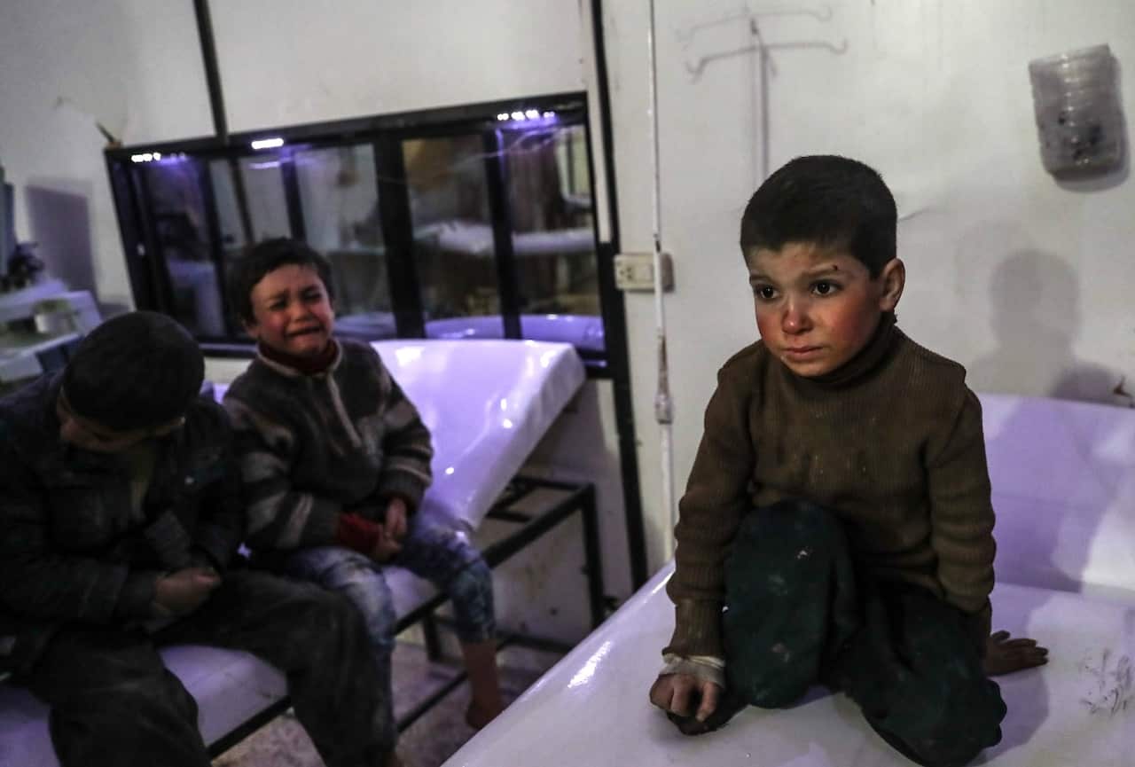 A Syrian boy receives a wounded kid at the field hospital after Assad Regime's airstrikes