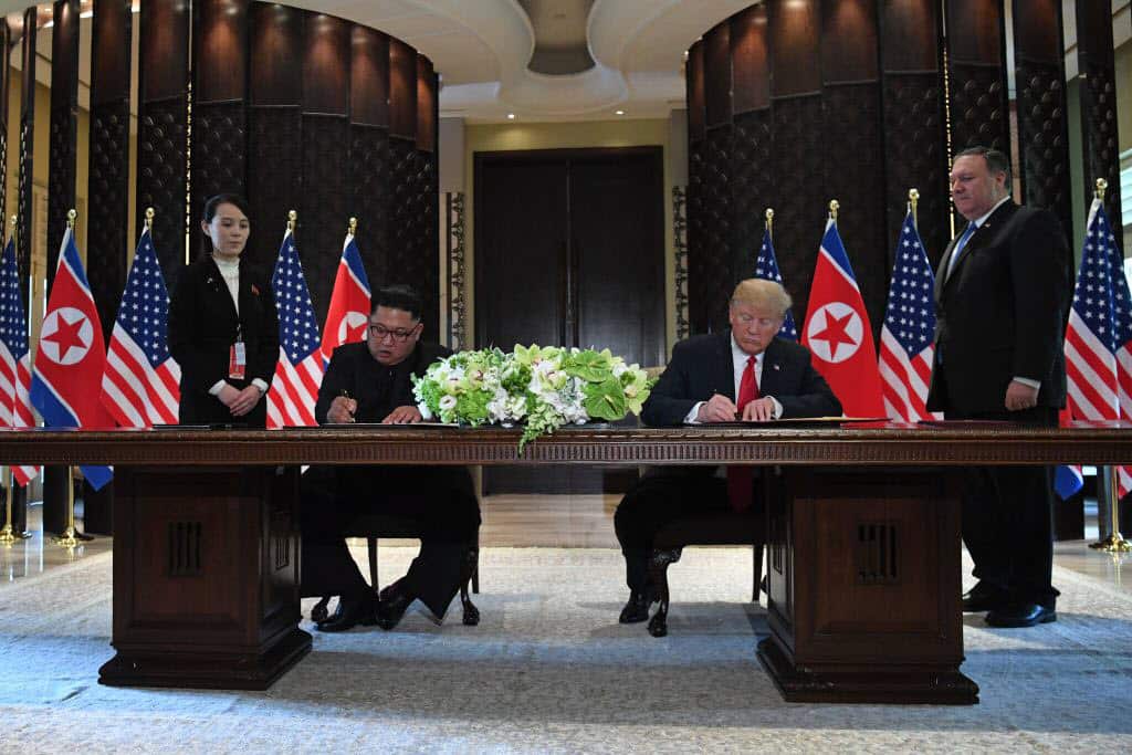 US President Donald Trump (2nd R) and North Korea's leader Kim Jong-un (2nd L) sign documents.