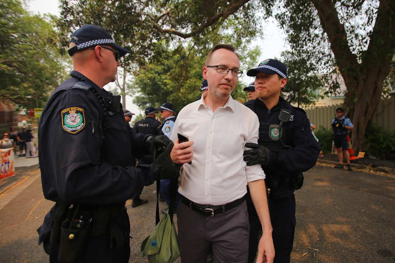 The Greens MP is led from the scene of the protest by police. 