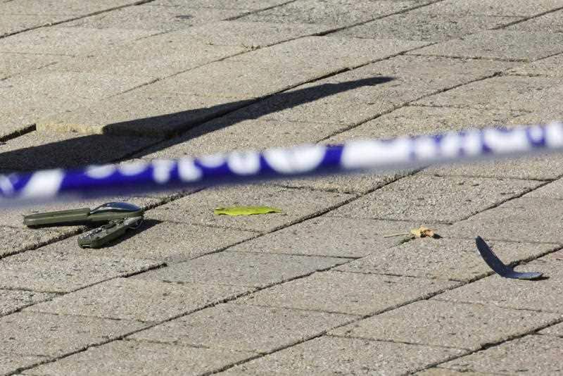 Parts of a knife lay on the ground behind a police cordon as police investigate the scene.