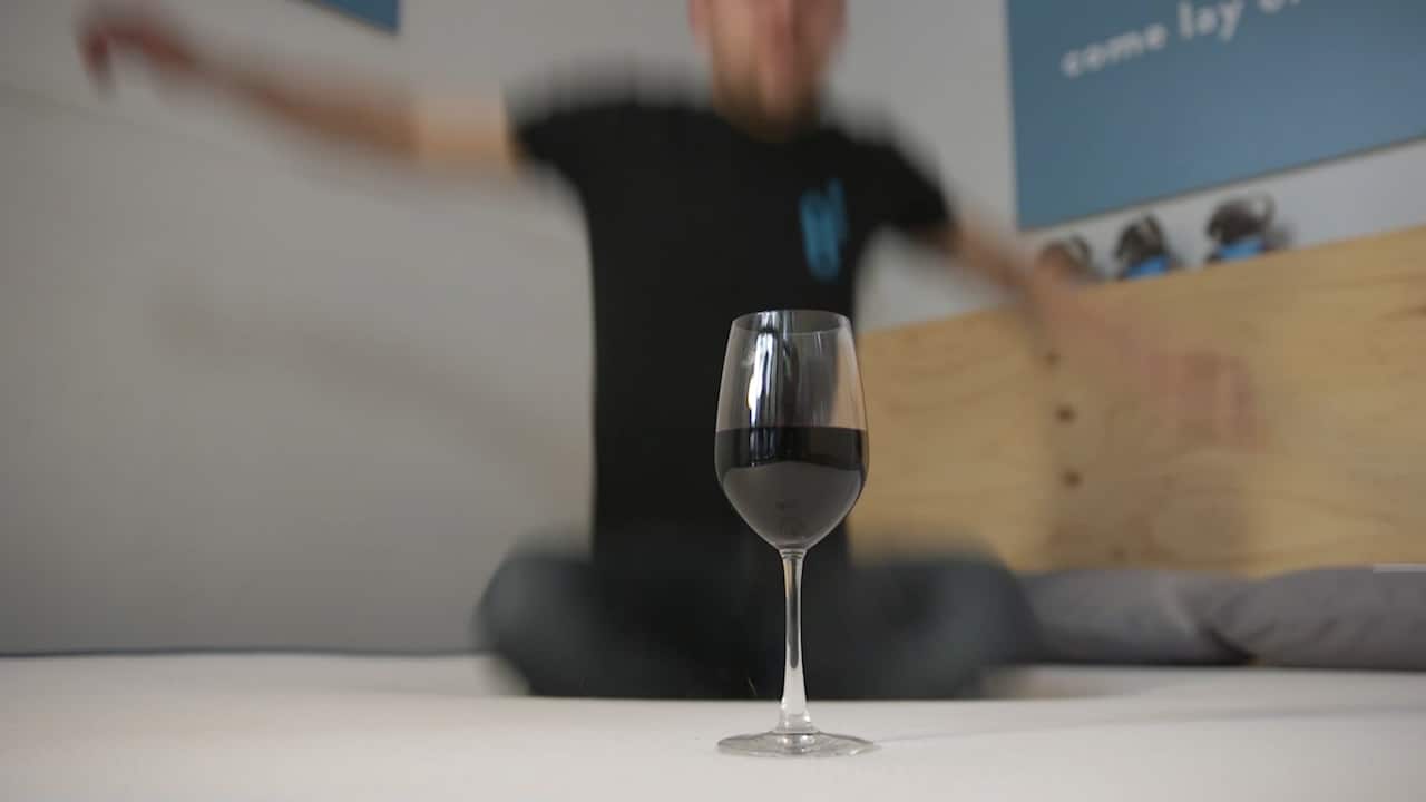 A staff member jumps near a wine glass to test the mattress' zero disturbance feature.