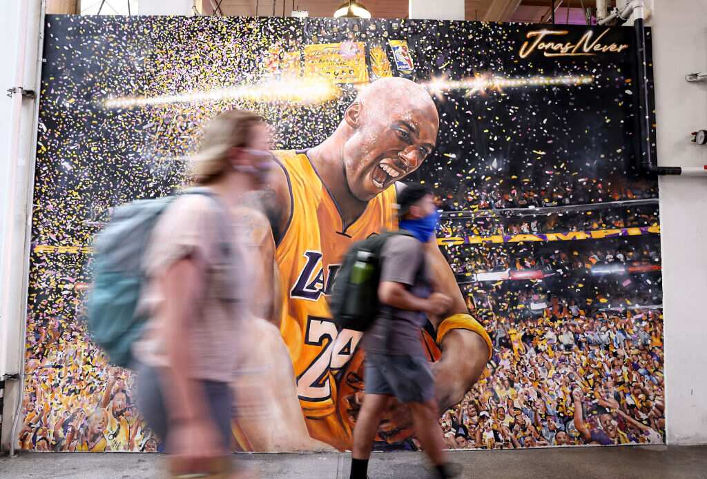 People wear face coverings while walking by a Kobe Bryant mural in Los Angeles, California. A new mask mandate went into effect just before midnight on 17 July.