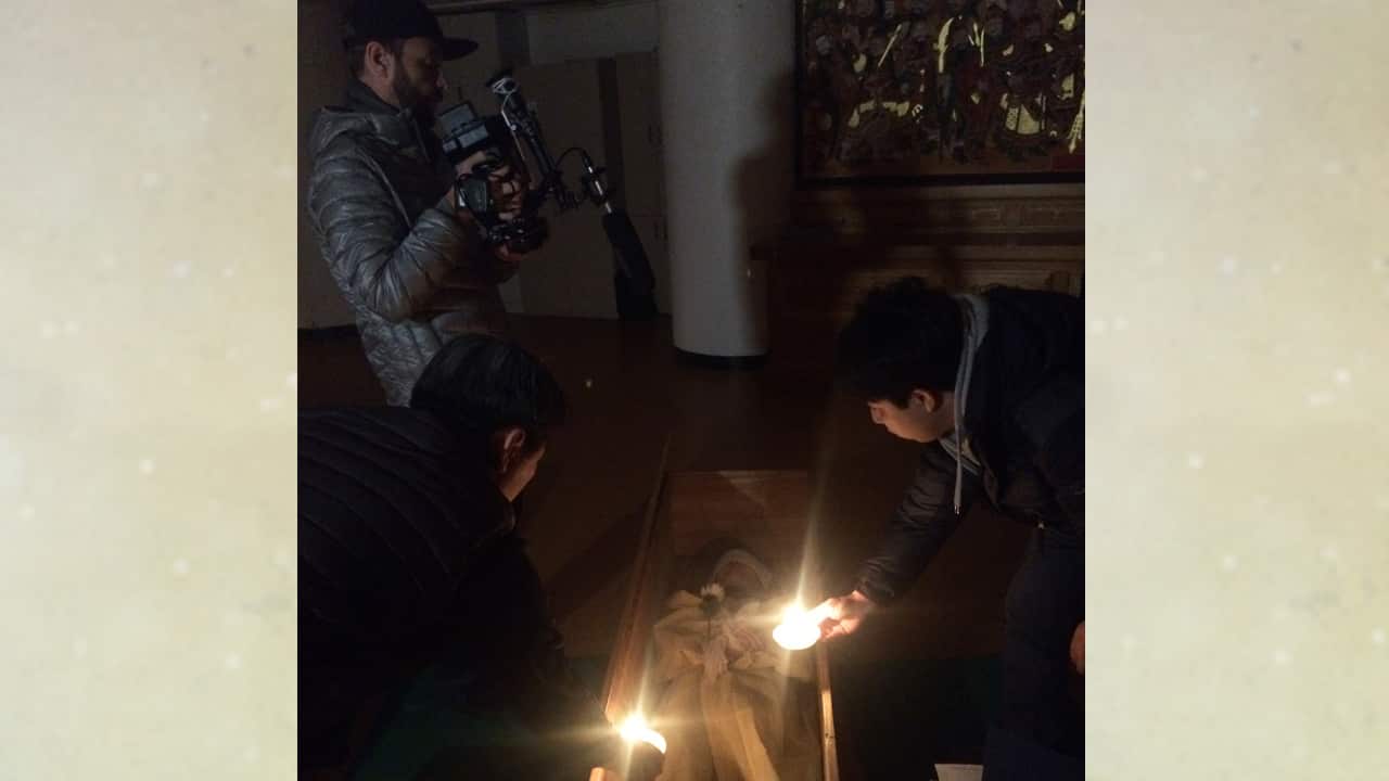 Dean films by candlelight as the participants take their places in their coffins.