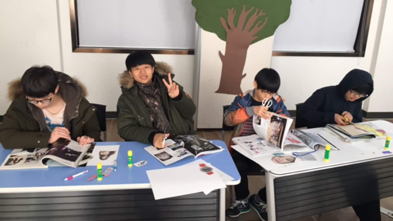 There's no technology in this classroom, so no wonder Dean's camera attracts the attention of Kyung Seo.