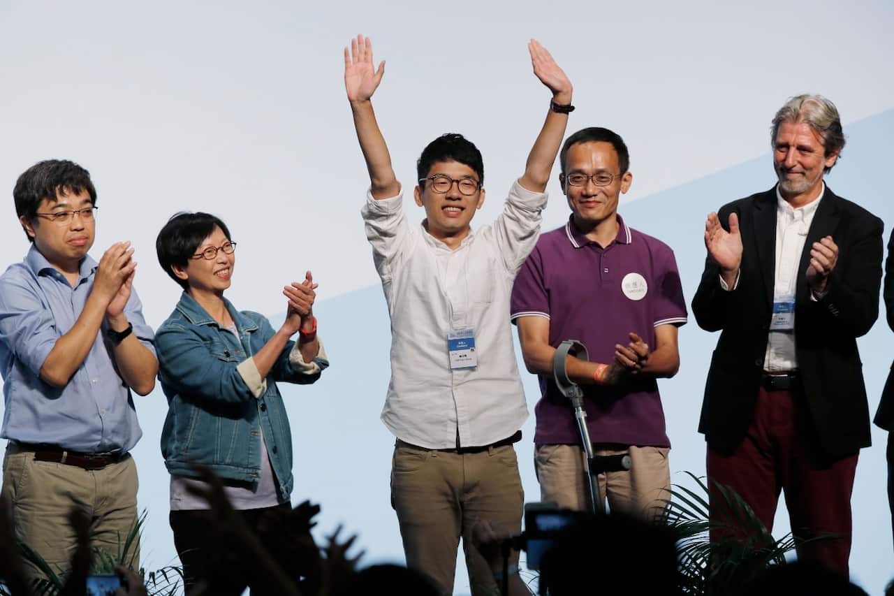 Student Nathan Law, center, who helped lead the 2014 protests, celebrates after winning a seat at the legislative council elections in Hong Kong (AAP)