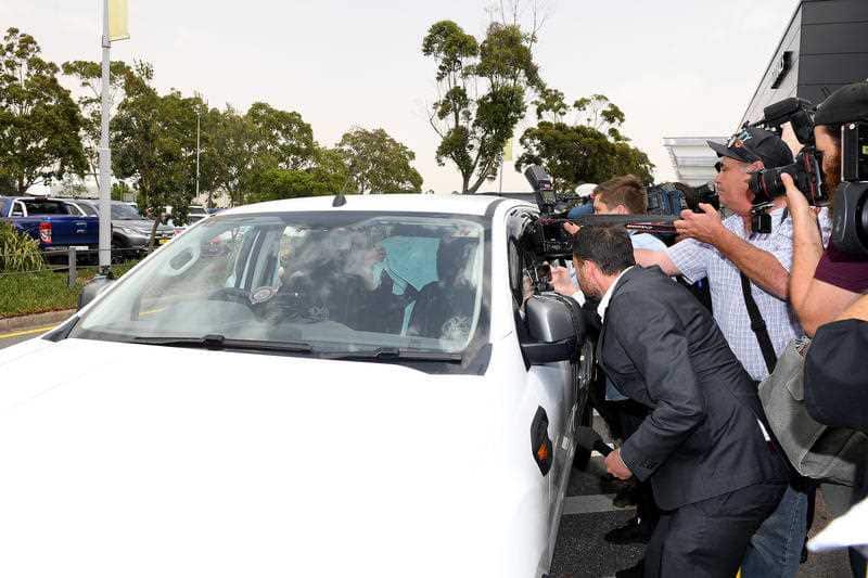 Bali Nine drug smuggler Renae Lawrence covers her head with a towel as her car is surrounded by media after arriving at Newcastle airport.