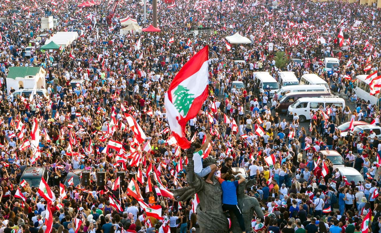 Protesters wave Lebanese flags and shout anti-government slogans during a protest in front of  Muhammad al-Amin Mosque in downtown Beirut.