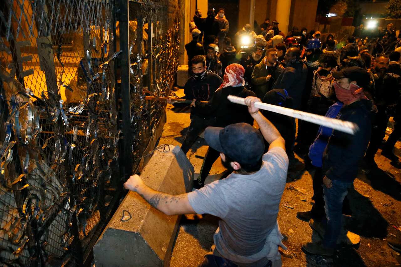 Anti-government protesters use sticks to break through metal security gates outside the central government buildings in Beirut.