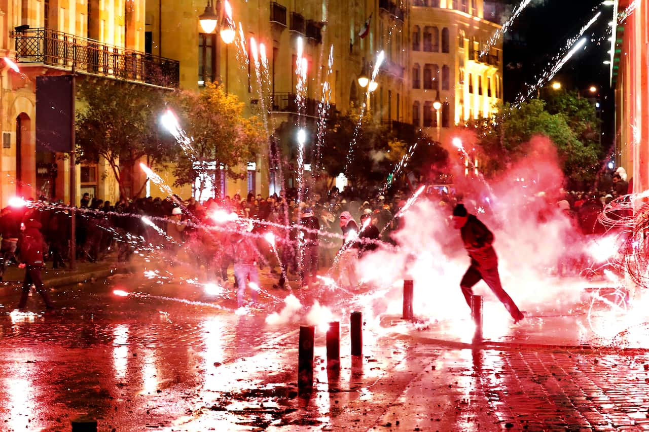 Anti-government protesters throw firecrackers at riot police.