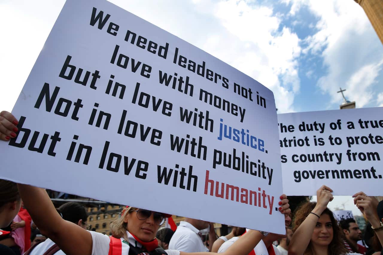 Anti-government protesters hold placards as they protest, in downtown Beirut.