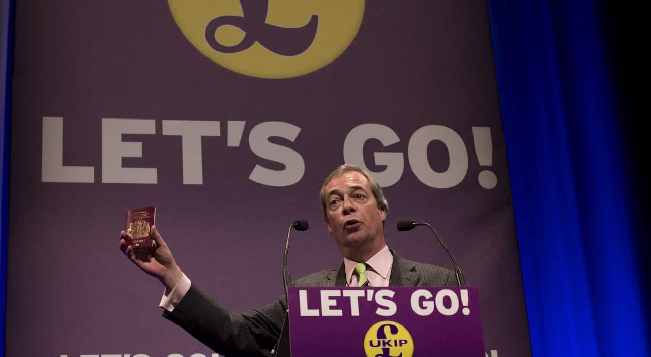 British politician Nigel Farage holds up a British Passport which he would like to see without European Union written on it (Getty)
