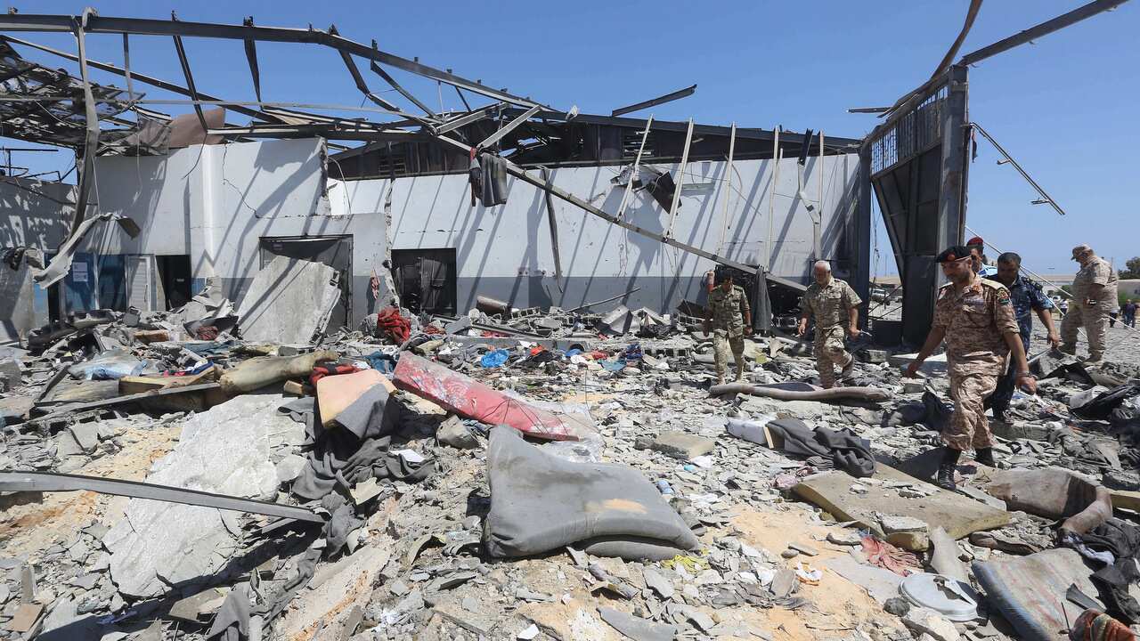 Migrants check the rubble of the destroyed detention centre.