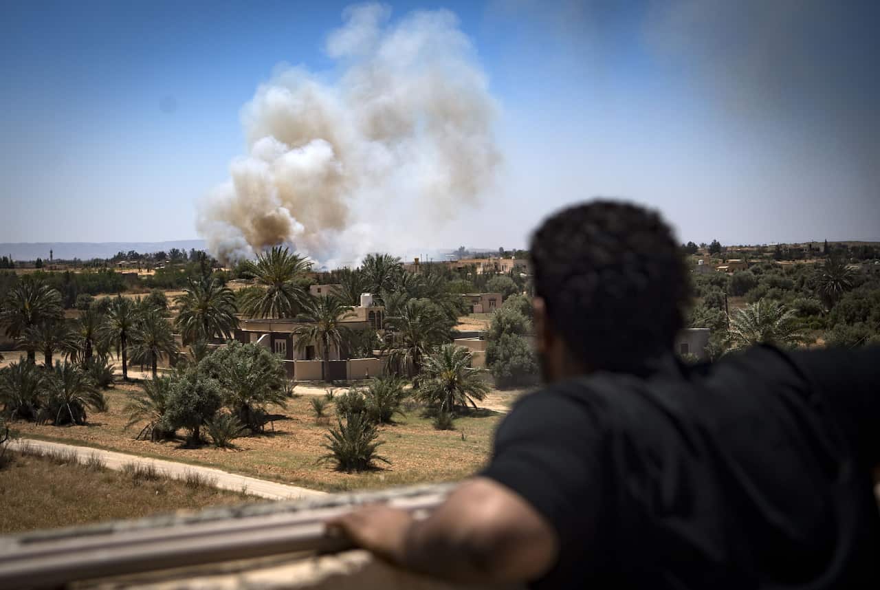 A fighter loyal to the Government of National Accord (GNA) watches as smoke rises in the distance during clashes with forces loyal to strongman Khalifa Haftar.