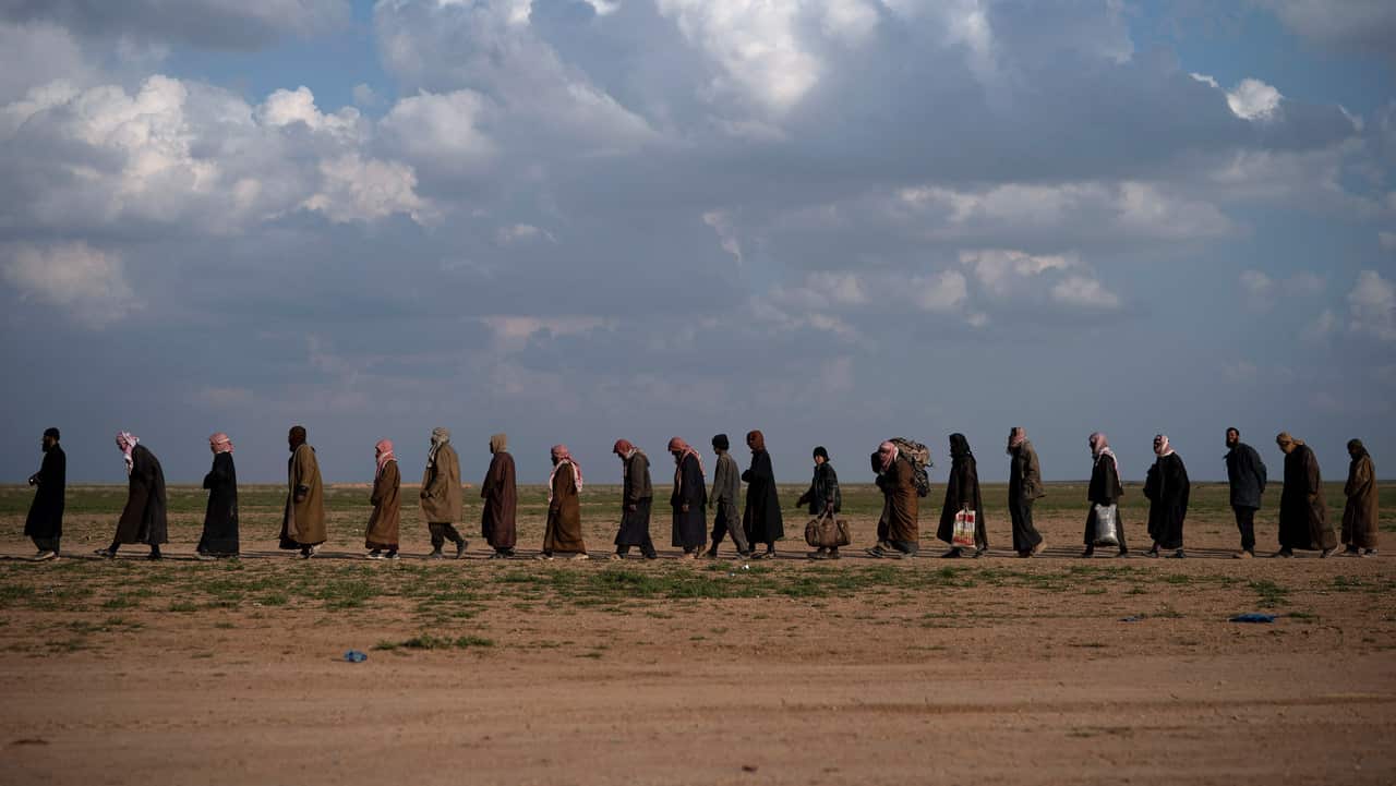 Men walk to be screened after being evacuated out of the last territory held by IS militants, near Baghouz, eastern Syria.