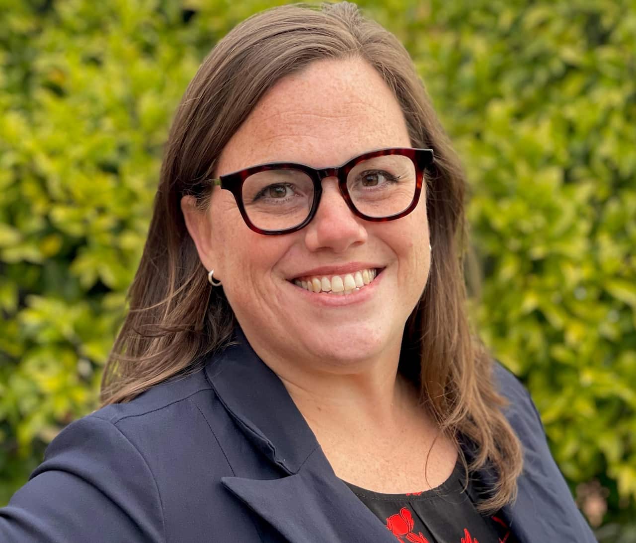 A woman with glasses and brown hair smiling