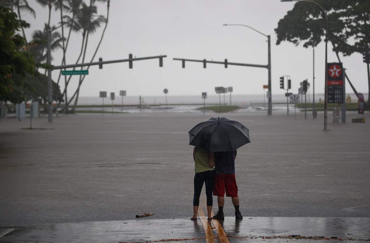  Michelle Montgomery (L) and Eric Leifer (R) share a moment under an umbrella, as they view the flooded Pauahi St and Kamehameha Ave intersection in Hilo
