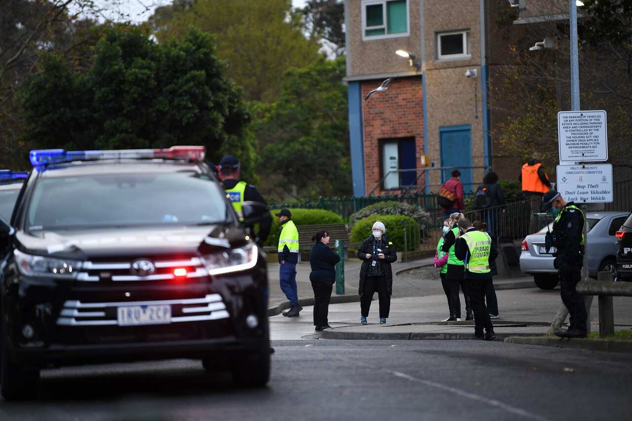 Victorian Police officers and health workers are seen outside a public housing tower along Racecourse Road in Melbourne.