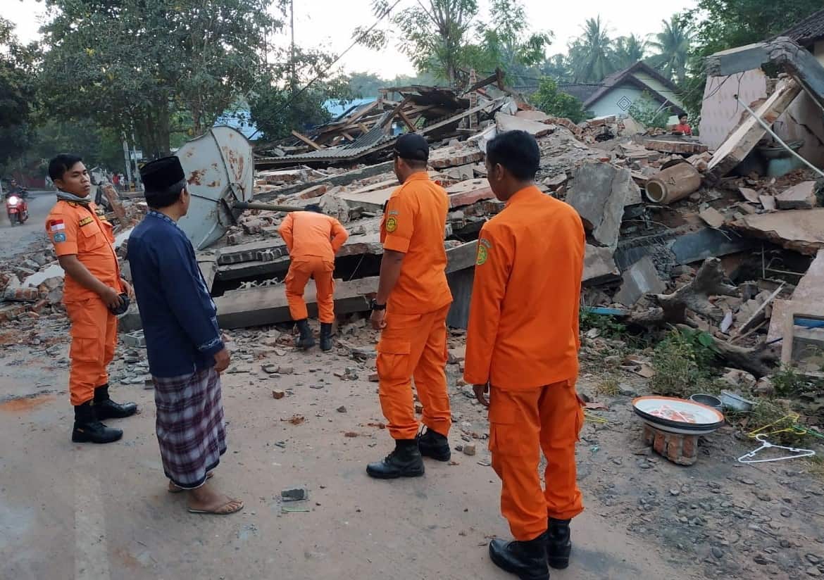 A handout photo made available by Indonesian Search and Rescue (Basarnas) shows rescuers inspecting collapsed houses after an earthquake struck 