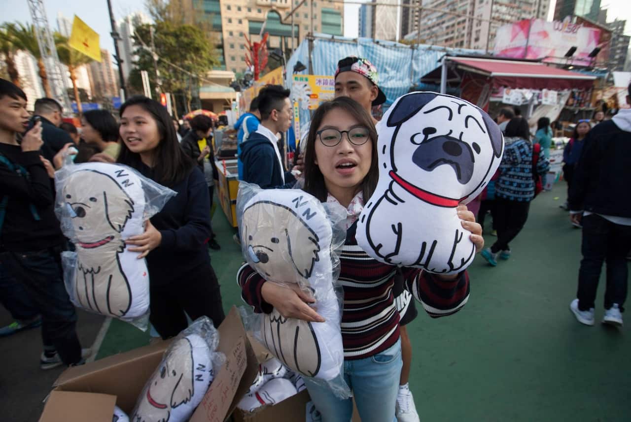 Young people sell stuffed dog-themed toys ahead of the Chinese New Year of the Dog which arrives on 16 February 2018 in Hong Kong